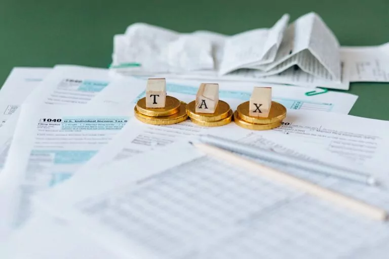 A bunch of paperwork with the word "TAX" spelled using wooden letters.